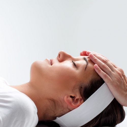 woman-relaxing-at-reiki-session--480118982-5aeda463c5542e0036ccdd4c